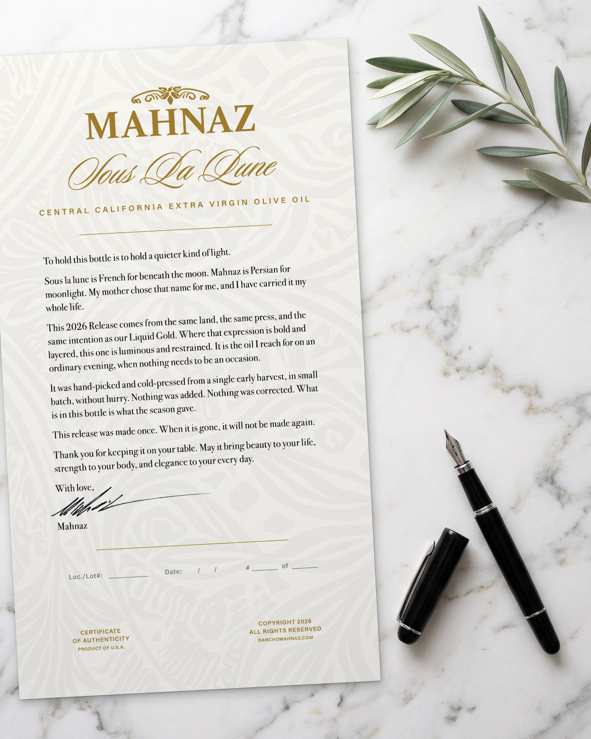 The Sous La Lune certificate of authenticity, signed by Mahnaz, on white marble with an olive sprig and a fountain pen