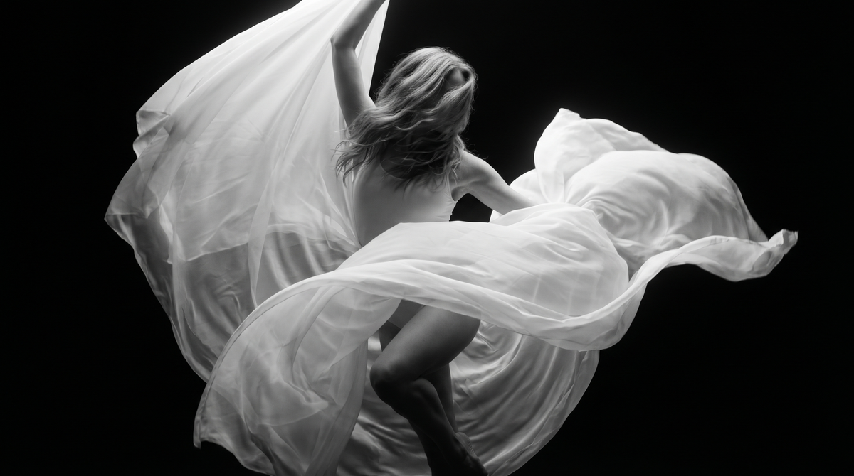 A dancer in flowing white fabric, in black and white